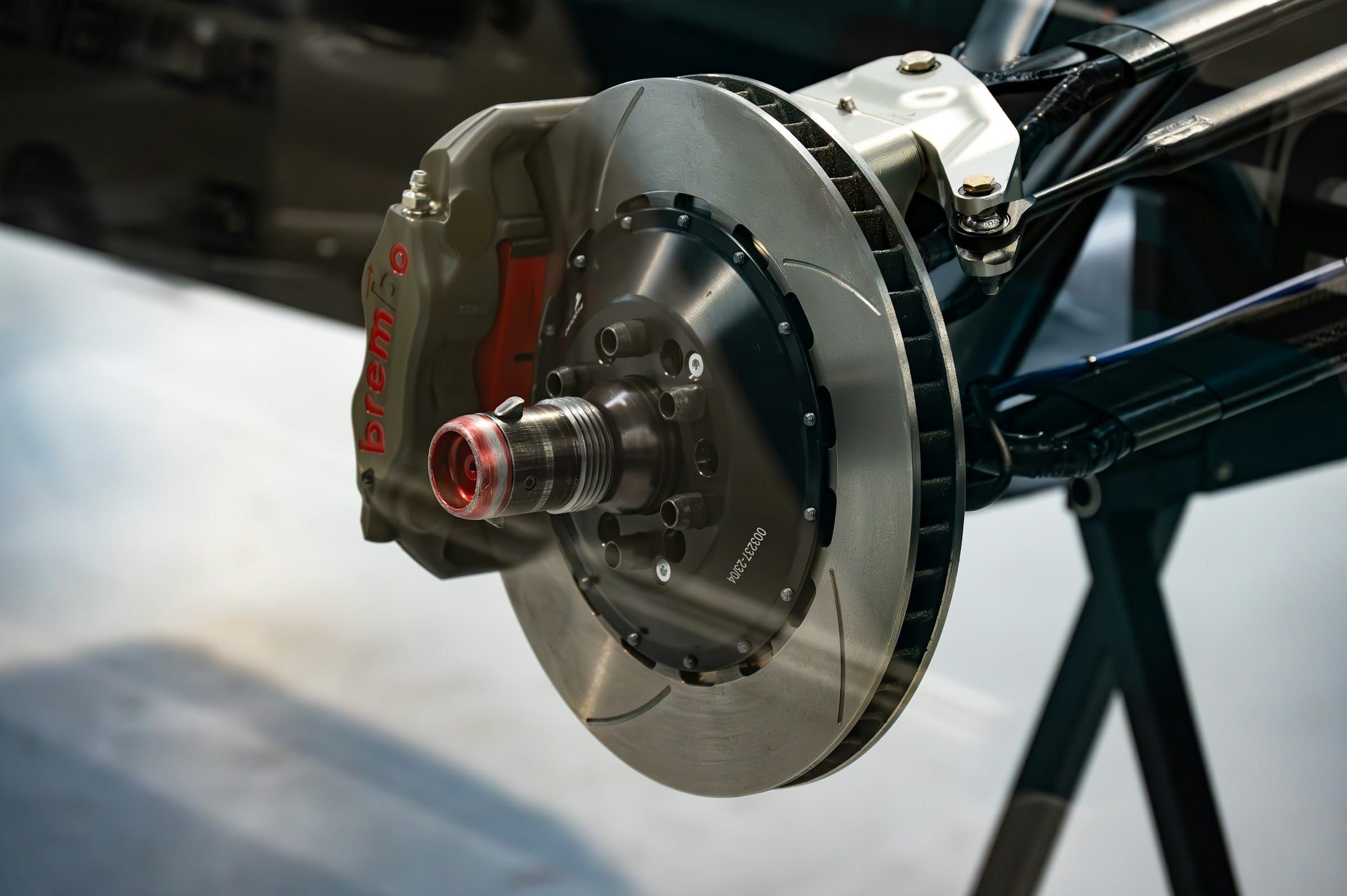 Close-up of a ventilated brake disc and a red Brembo calliper on the suspension of a car in a workshop